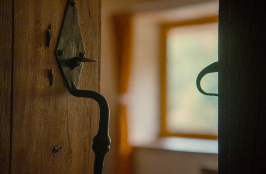 Une poignée de porte ancienne, la fenêtre en arrière-plan