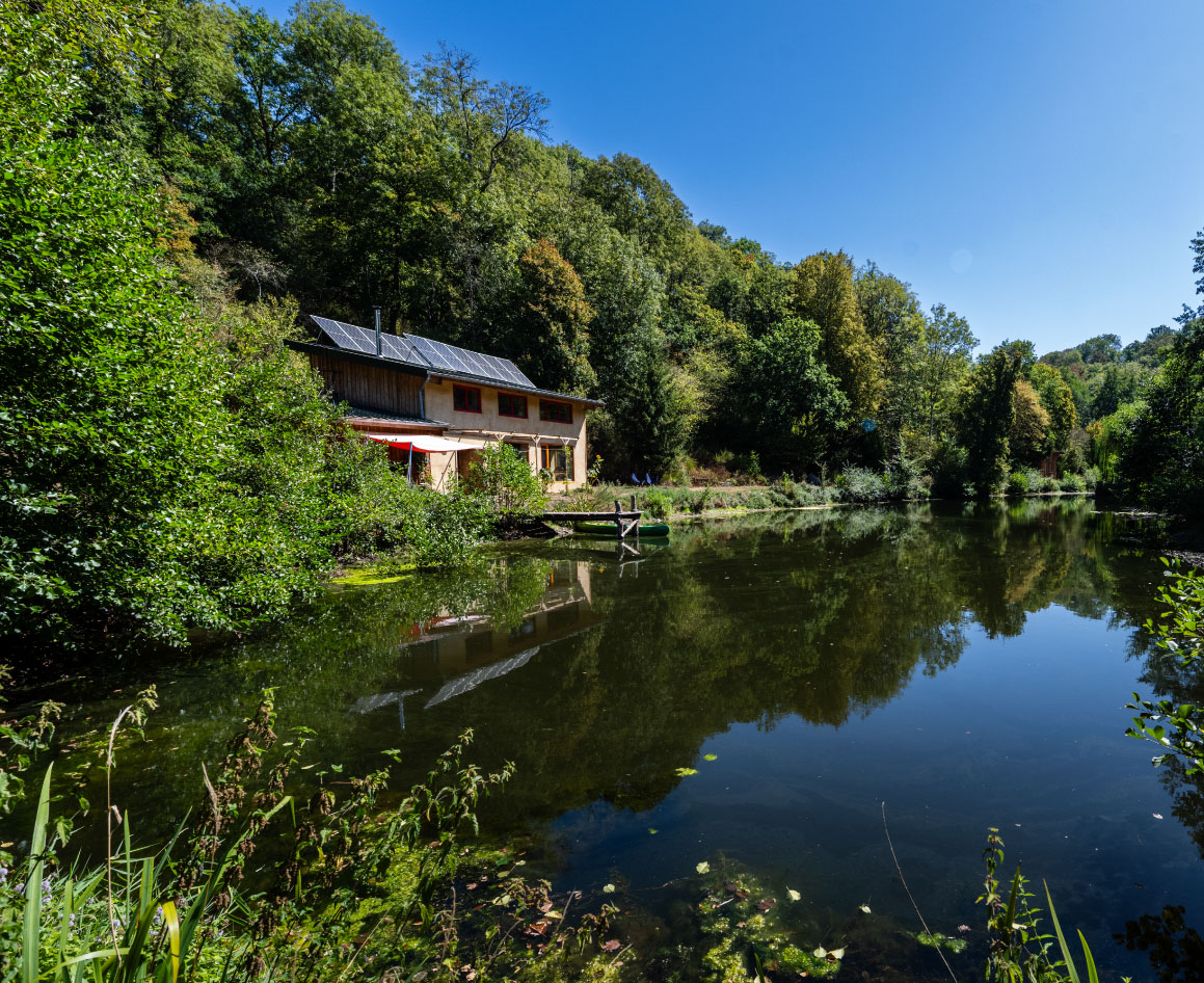 La maison de la ferme au bord de l’étang, entourée d’arbres