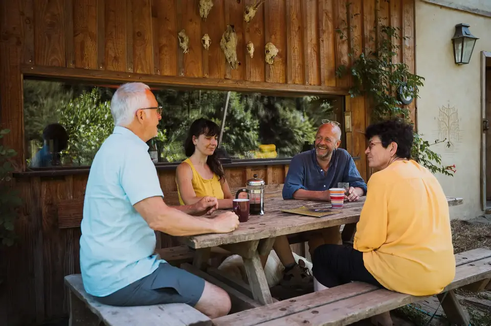 Quatre personnes discutent autour d'une table de pique-nique sous l'auvent
