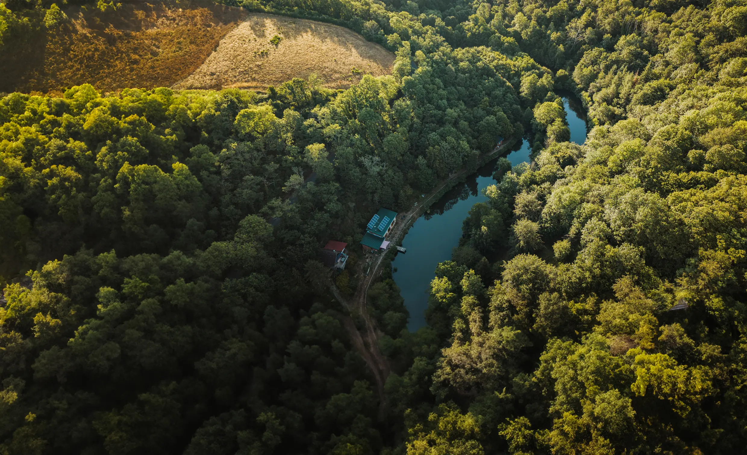 Vue aérienne de la vallée boisée et de la ferme au bord de la rivière